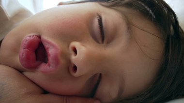 Derin uykuda bir çocuğun yüzüne yakın çekim yapmak, çocukluk uykusunun huzurlu ve huzurlu doğasını vurgulamak, yumuşak ve rahat yüz hatlarıyla masumiyeti gösteriyor.