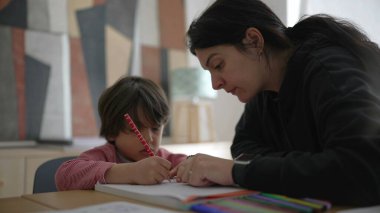Çocuğa okul ödevlerinde yakından yardımcı olan ebeveyn, detaylı rehberlik ve bakım evi ortamında odaklanmış öğrenme, kendini adamışlık ve destek gösterme