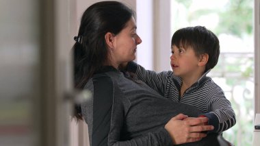 Hamile kadın çocuğuyla birlikte oturuyor, ev ortamında, sevgi dolu etkileşimler, pencereden gelen doğal ışık, aile bağı, anne beklentisi, hassas an, ev ortamı, huzurlu ve huzurlu sahne