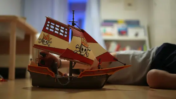 Stock image Boy playing with a toy ship on the floor, fully absorbed in imaginative play, enjoying his creative and playful moment