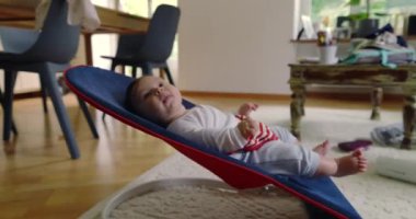 Bebek bir fedaide yatıyor, gülümsüyor ve mutlu görünüyor, rahat bir ev ortamında rahatlık ve rahatlığın tadını çıkarıyor, çocukluk yıllarının masumiyetini ve neşesini vurguluyor.