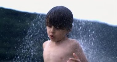 Elleri havada su sıçratarak oynayan bir çocuk, o anın şaşkınlığını ve neşesini vurguluyor, 800 fp 'de yavaş çekim yakalanıyor.