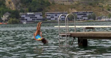 Çocuk, 800 fps hızla yavaş çekimde bir platformdan göle balıklama atlıyor. Su kenarında geçirilen yaz gününün coşkusunu ve eğlencesini gözler önüne seriyor.