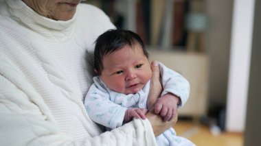 Yakın plan yeni doğan bebek. Yaşamın ilk günlerinde büyükanne tarafından kucağa alındı. Bebeğin ilk aşamaları, ilk haftası.