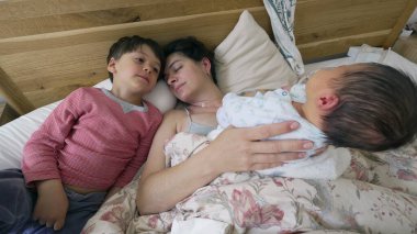 Aile sahnesi. Anne ve oğul yeni doğan bebeğe bakıyor. Yatakta yatıyor. Kardeşi ve annesi ailenin yeni üyesine kucak açıyor.