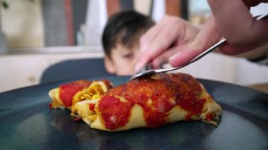 Ebeveynlerin elleri tabakta ev yapımı enchilada keserek, çocukların aile yemeği sırasında yemeğin tadını çıkarmasını kolaylaştırıyor.