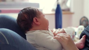 Annenin yeni doğmuş bebeğini kucağına alıp, onların ellerine ve aralarındaki bağlara odaklandığı, yumuşak, rahat bir ortamda sevgi ve şefkat gösterdiği yakın plan.