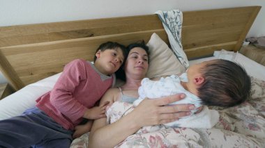 Aile sahnesi. Anne ve oğul yeni doğan bebeğe bakıyor. Yatakta yatıyor. Kardeşi ve annesi ailenin yeni üyesine kucak açıyor.