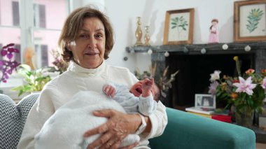 Yeni doğmuş bebeği kucağına aldığı için mutlu bir büyükanne. Oturma odasındaki koltukta oturup ağlayan bebekle ilk günlerinde iletişim kuruyor.