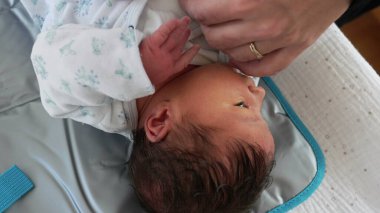 Annenin yeni doğmuş bebeği giydirmesi, hayatının ilk günleriydi. Sıcak giysili bebek bakımı.