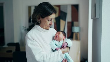 Büyükanne kucağında ve yeni doğmuş bebek torunu kollarında tutarken hayatın ilk günlerinde pencerede dikilirken, özgün aile bağı anı