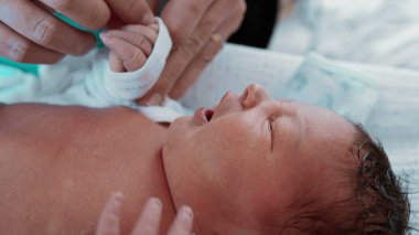 Yeni Doğan Bebek - Anne Bebek Elleri, Yakın plan. Bir annenin, yeni doğmuş oğlunun minik ellerini giydirip, anne ile çocuk arasındaki bağın altını çizdiği hassas bir an.