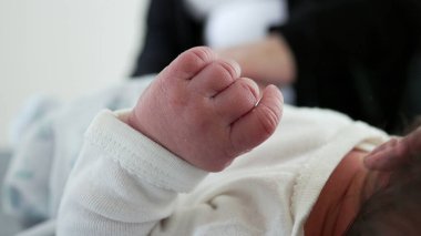 Yaşamın ilk günlerinde küçücük bir bebeğin elleri. Anne onu bulanık bir arka plan ile giydirirken yeni doğmuş bir bebeğin el işi.