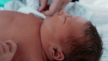 Yeni Doğan Bebek - Anne Bebek Elleri, Yakın plan. Bir annenin, yeni doğmuş oğlunun minik ellerini giydirip, anne ile çocuk arasındaki bağın altını çizdiği hassas bir an.