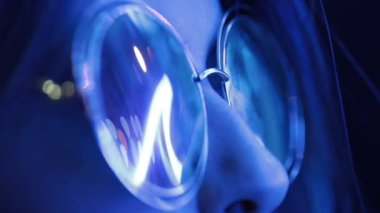 Geceleyin neon ışığı yansıması ile büyük yuvarlak güneş gözlüğü takan kız.