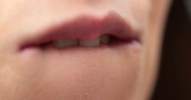 Dudaklarını ısıran genç bir kadının makro yakın çekimi.