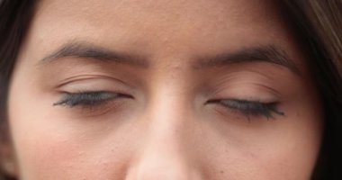 Makro, kameraya bakan genç kadın gözleri. Kız gözlerini kapar.