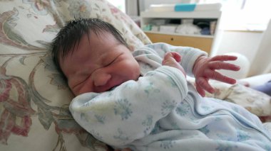 Yeni doğmuş bebek. Kollarını ve vücudunu oynatıyor. Ömrünün ilk günlerinde anne ve kardeşiyle yatak odasında şikayet ediyor.