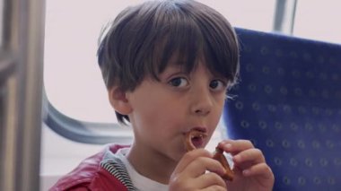 Trende çerez yiyen genç bir çocuk, yolculuk sırasında çocukluk keyfi ve keşif anı, genç bir maceracının yolculuğunun basit zevklerini ön plana çıkarıyor.