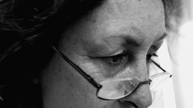 Gözlük takan yaşlı bir kadının siyah ve beyaz yakın plan çekimleri derin düşüncelere dalmış. içsel ruh hali ve bilgelik