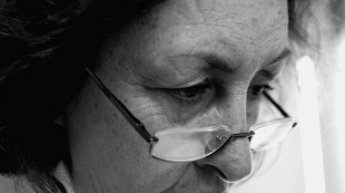 Gözlük takan yaşlı bir kadının siyah ve beyaz yakın plan çekimleri derin düşüncelere dalmış. içsel ruh hali ve bilgelik