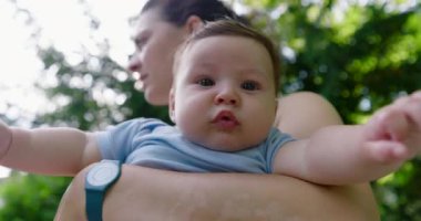 Genç anne yaz parkında bebek taşıyor.