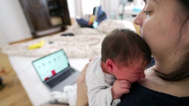 Anne, tamamen yeni doğmuş bebeğine odaklanmak için dizüstü bilgisayarını kapatıyor. Aile bakımını işe tercih ettiği hassas bir an. Modern anneliğin duygusal bağını ve adanmışlığını vurguluyor.