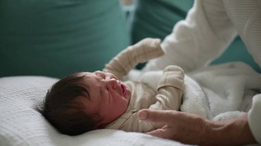 Yeni doğmuş bir bebeğin ağlaması, kanepenin üzerinde yumuşak bir battaniyeye uzanması, yanında şefkatli bir büyükanneyle, erken çocukluk ve aile etkileşiminin anlarını yakalaması.