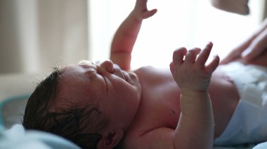 Yeni doğmuş bebek uzanmış, sadece bebek bezi giyiyor, yumuşak ışıkla aydınlatılıyor, hayatın ilk anları, narin cilt ve yüz hatlarını gösteriyor, huzurlu ve huzurlu bir sahne, masumiyeti vurguluyor.