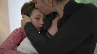 Bir anne kucağında yeni doğmuş bir bebeği kollarında tutarken küçük oğlunu teselli eder. Şefkat ve sevgi dolu bir anı paylaşır. Günlük kıyafetler giyer, duygusal bağ kurar, ebeveynlik yapar, aile desteğini paylaşır.