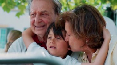 Genç çocuk, sevgi, aile bağları ve kuşak sevgisiyle dolu bir sahneyi çekerek, büyük anne ve büyük babasıyla sevgi dolu bir anı paylaşıyor.