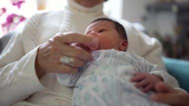 Yeni doğmuş bebek, büyük ebeveynlerinin elinde tutularak dünyaya merakla bakıyor. Farklı nesiller arasında paylaşılan değerli bağı ve sevgiyi vurguluyor.