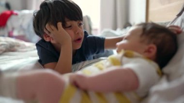 Büyük kardeş yatakta uzanıyor, küçük kardeşleriyle düşünceli bir sohbete girişiyor. Samimi an, iki kardeş arasındaki yakın bağı ve bağlantıyı yansıtır.
