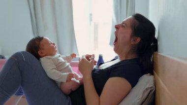 Anne, neşeli bir ifadeyle cevap veren bebeğine sevgiyle bakar. Parlak, huzurlu bir yatak odasında samimi bir yakınlık ve sevgi anı paylaşır.