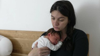 Anne laptopta çalışmak ile bebeğine bakmak arasında gidip geliyor. Modern çalışan ebeveynlerin gerçekliğini gösteriyor. Mesleki görevlerini ebeveynlik, sevgi ve evdeki aile sorumluluklarıyla dengeliyor.