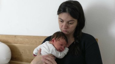 Anne laptopta çalışmak ile bebeğine bakmak arasında gidip geliyor. Modern çalışan ebeveynlerin gerçekliğini gösteriyor. Mesleki görevlerini ebeveynlik, sevgi ve evdeki aile sorumluluklarıyla dengeliyor.