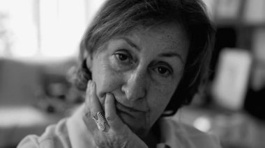 Düşünceli ve içsel bir ifadeyle, kendi bilgeliğini, hayat deneyimini ve düşüncelerinin derinliğini yansıtan bir anda vurgulayan, yakın plan bir portrede çekilmiş yaşlı bir kadın.