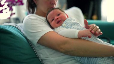 Anne bebeğini bir koltukta oturarak destekliyor ve çocuğu rahatlatıyor. Bir annenin bebeğinin iyiliği için gösterdiği ilgi ve ilgiyi yansıttığı an.