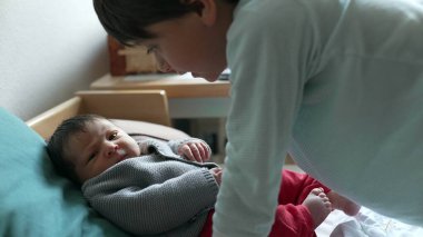 Büyük kardeş yeni doğmuş bir bebeğe sarılıyor. Yürek ısıtan bir kardeş sevgisi ve bağ kurma anı yaratıyor. Evdeki sevgi dolu aile ortamını yansıtıyor.