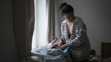 Anne sevgiyle yeni doğmuş bebeğini pencerenin yakınındaki bir masanın üzerine koyar, sıcak bir evde huzurlu ve şefkatli bir anı yakalar.