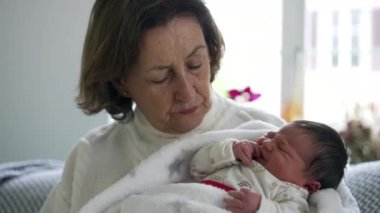 Büyükannem yeni doğan torununu kucağına aldı. Huzurlu bir yuvada sakin ve düşünceli bir bağ kurma anı.