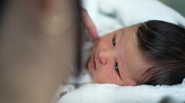 Yeni doğan bebeğin yakın plan portresi erken yaşlarda sıcak ve güvenli bir anı yakalıyor.