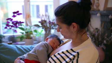 Anne, huzurlu ve besleyici bir anda uyuyan bebeğini kucağında tutuyor. Samimi sahne, anne ve bebek arasındaki derin bağ ve rahatlığı vurgular.