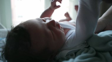 Yeni doğmuş bir bebeğin, bir yetişkin tarafından dikkatlice giydirilip hassas bir ebeveynlik anında gösterilen özen ve ilgiye dikkat edilmesi.