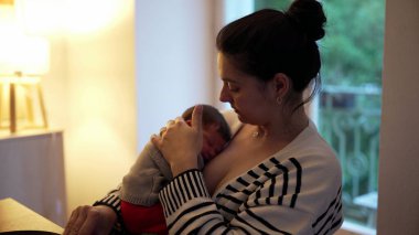 Anne, barışçıl bir bağ kurma anında yeni doğmuş bebeğini sevgiyle kucaklıyor. Hassas sahne anne ve çocuk arasındaki samimiyet ve bağlantıyı vurguluyor