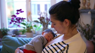 Anne, huzurlu ve besleyici bir anda uyuyan bebeğini kucağında tutuyor. Samimi sahne, anne ve bebek arasındaki derin bağ ve rahatlığı vurgular.