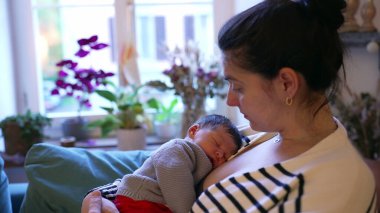 Anne, huzurlu ve besleyici bir anda uyuyan bebeğini kucağında tutuyor. Samimi sahne, anne ve bebek arasındaki derin bağ ve rahatlığı vurgular.