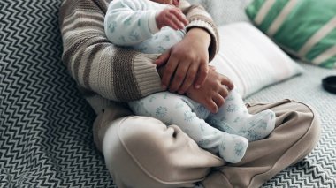 Rahat bir süveter giyen genç bir çocuk yeni doğan kardeşini desenli bir kanepeye yatırıyor. Bebek huzur içinde yatar. Oğlan da onları güvende tutar. Aile bağlarını kuvvetlendirir.