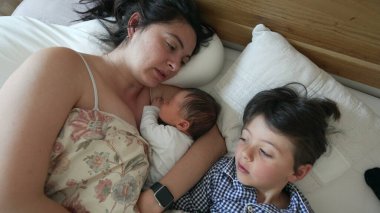 Anne beşikte yeni doğmuşken, büyük oğlu ona bakar, yakın aile bağı, sevgi dolu anne şefkati, sıcak ve şefkatli ortam, sabahın erken saatleri, kardeş bağı, anne bakımı