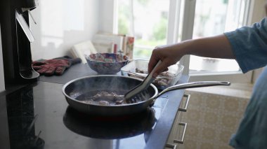 Anne, kucağında bebek uyurken yemek pişiriyor, çocuğunu beslerken ev işlerini yapıyor, ebeveynlik ve günlük sorumlulukların dengesini temsil ediyor.